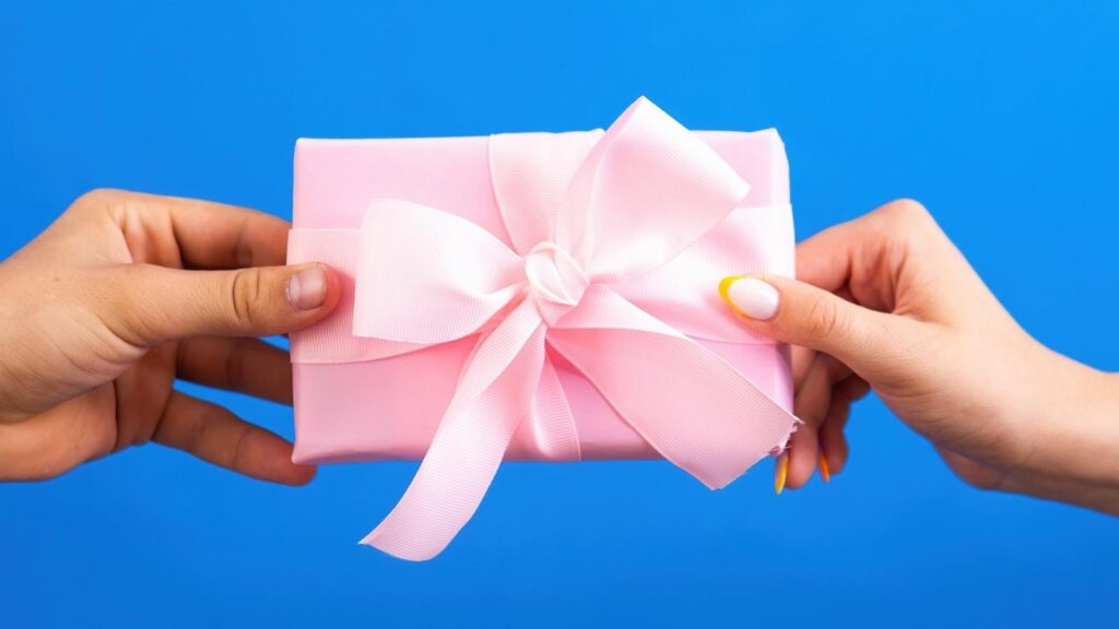 Hands holding pink present on a blue background.
