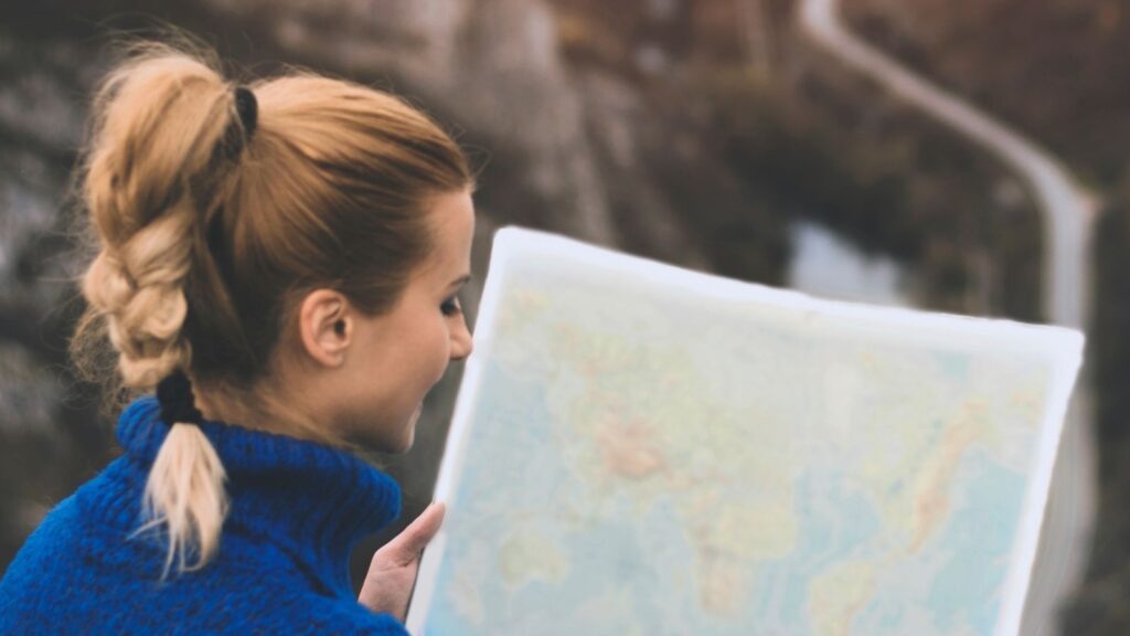 Woman looking at a paper map deciding on her next travel nursing or allied health destination.