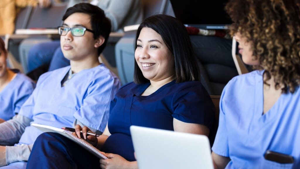 Multicultural and diverse nurses sitting and smiling watching a presentation.