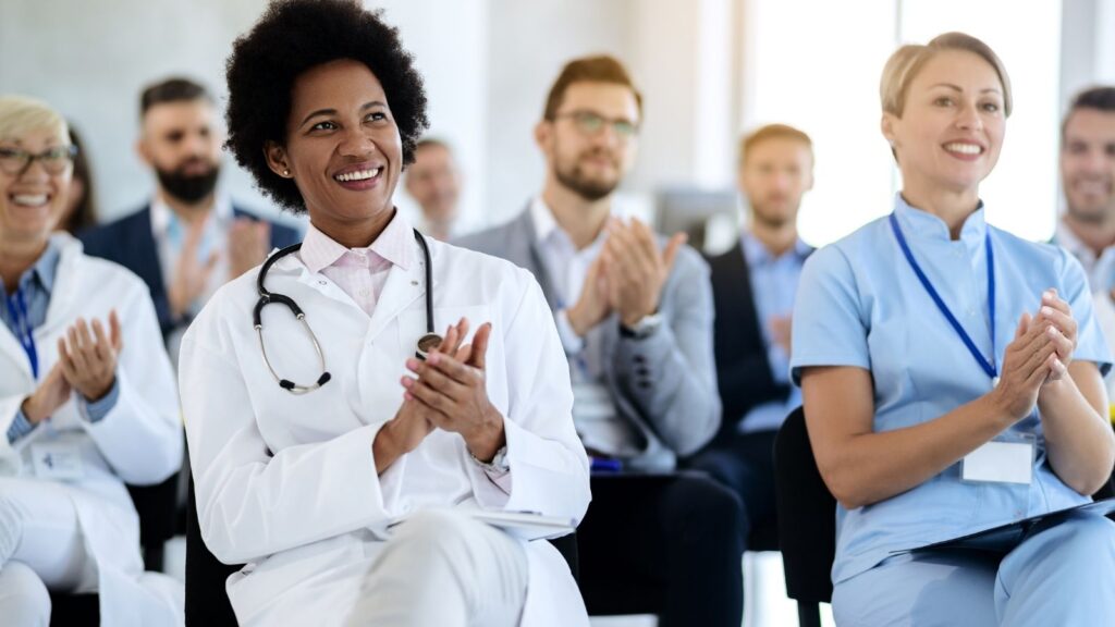Group of nurses sitting and applauding for the best travel nursing agency.