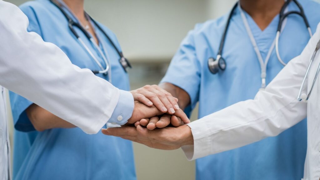 Travel nurses and allied health professionals putting their hands in a circle.