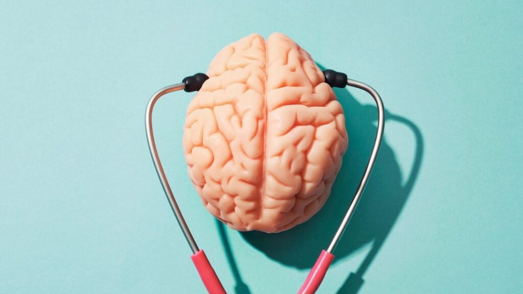 Pink rubber brain on a turquoise background with a stethoscope.