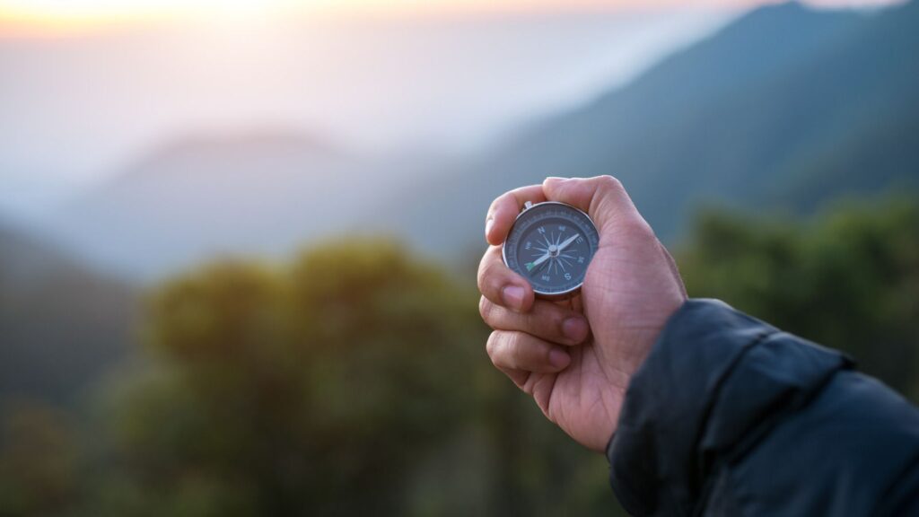 Traveler holding compass in hand on a hike in nature showing direction of how to become a travel nurse