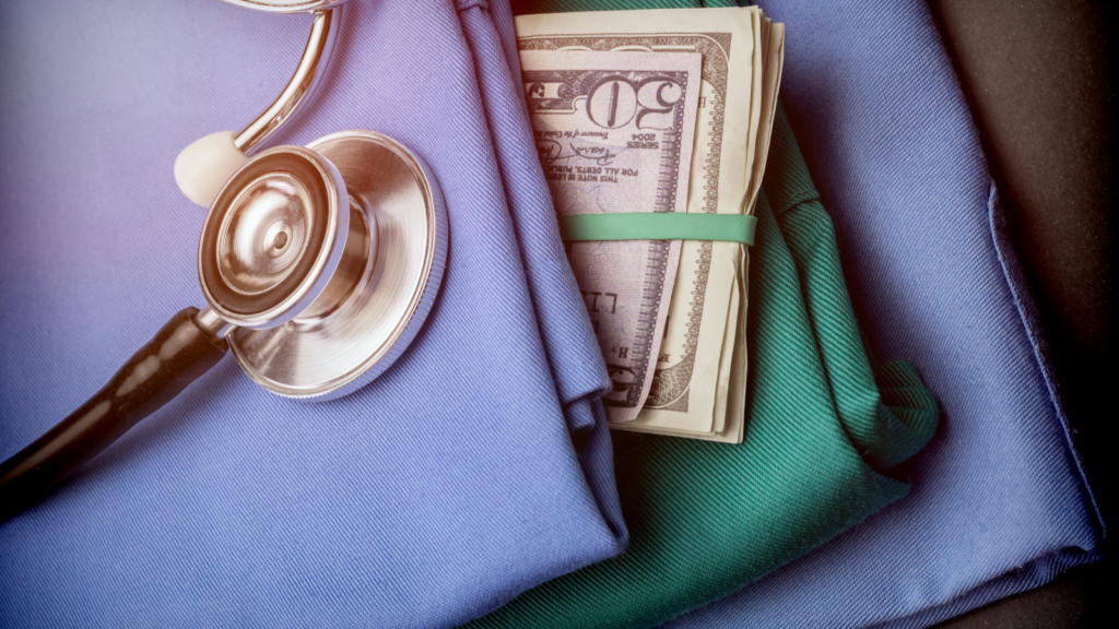 Money inside nursing scrubs with stethoscope.