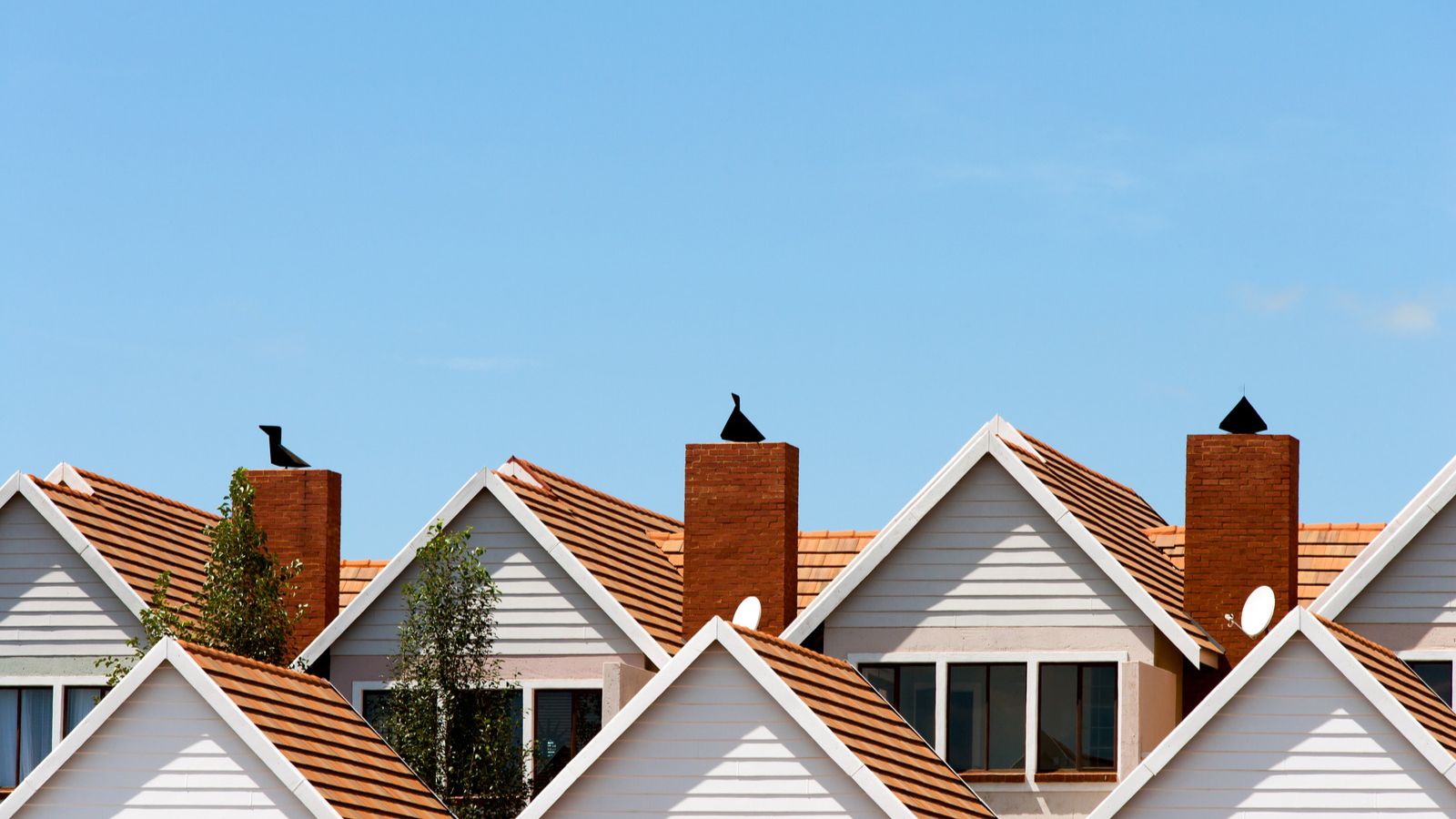 Group of white and brown houses in front of the blue sky. Housing stipend.