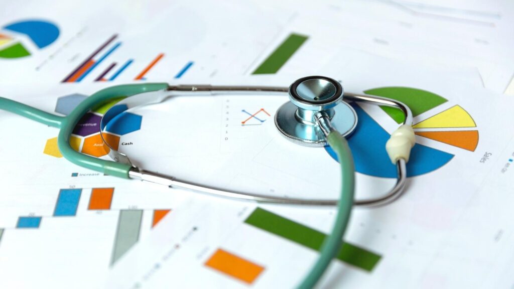 Stethoscope on top of medical graph reports on a table.