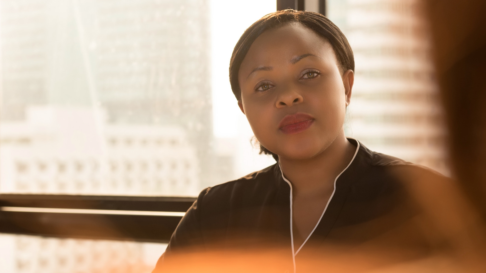 Black woman sitting in front of window smiling softly.