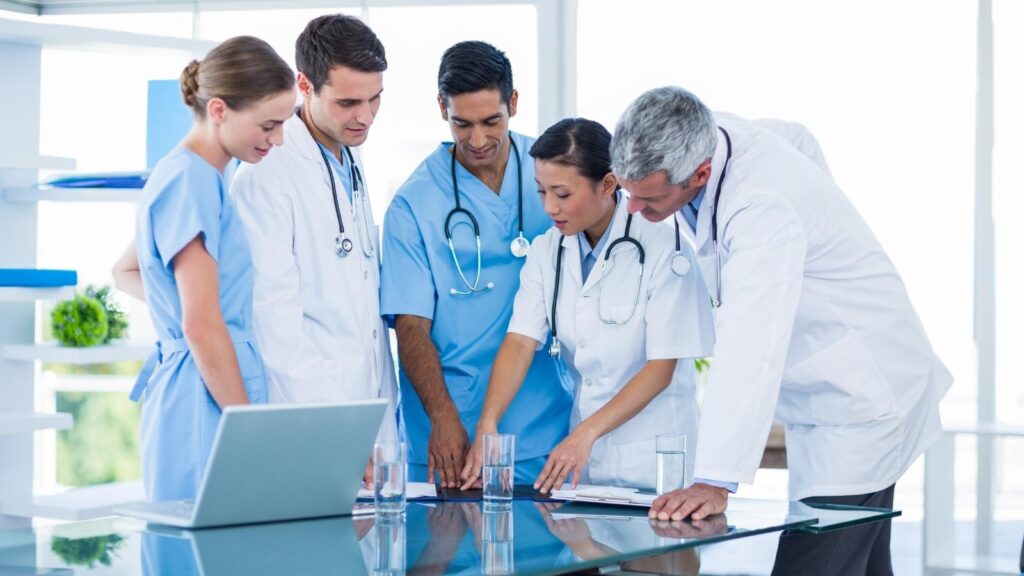 Group of diverse nurses and doctors examining a report on a table in a meeting.