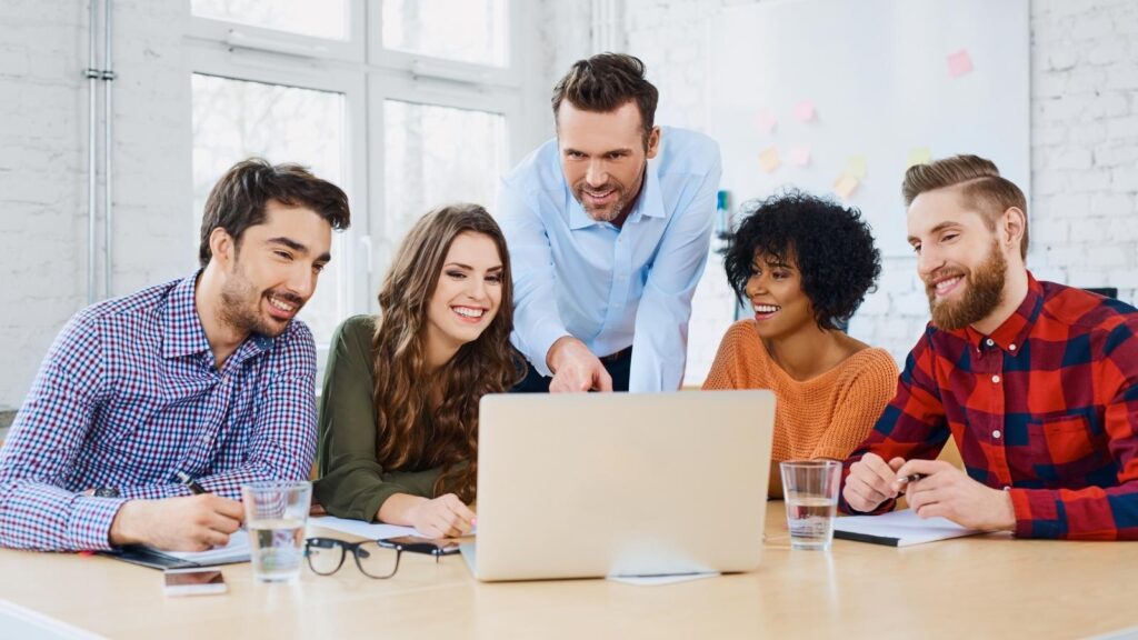 Young professionals gathered around a laptop on the table.