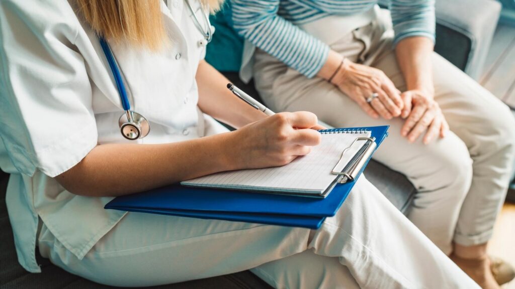 Nurse sitting down and charting on a clipboard.