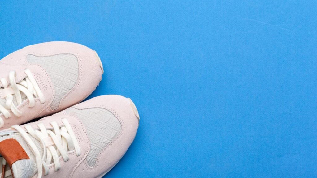 White nursing shoes in the corner on light blue flooring.