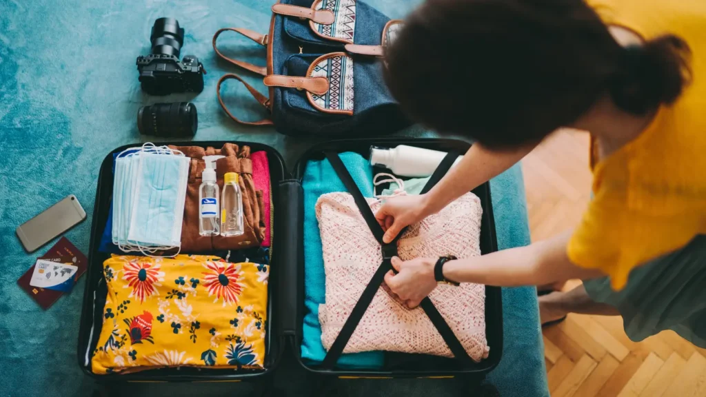 Woman wearing a yellow shirt packing a luggage for a travel nurse assignment