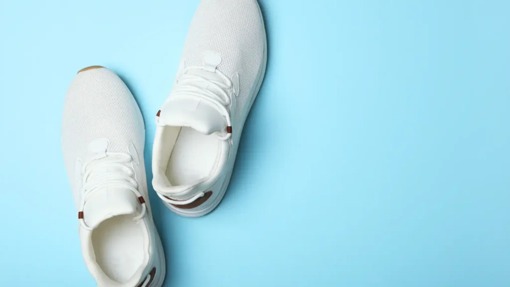 Pair of white male nurse shoes arranged on a light blue background.