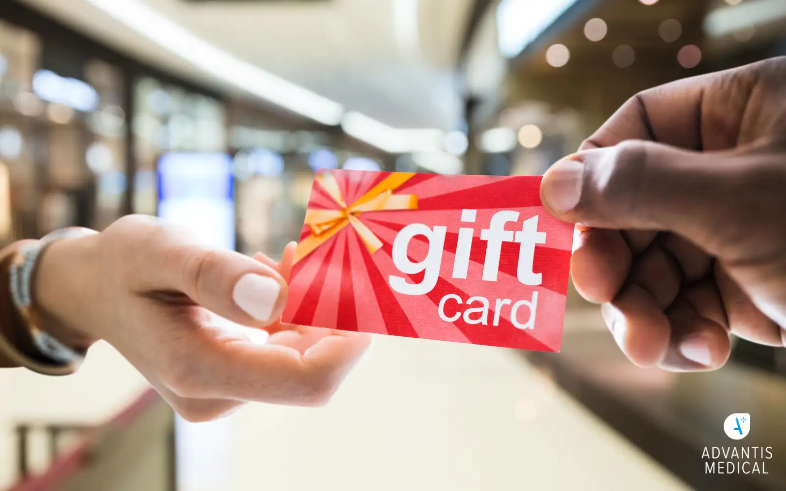 Close up of hands belonging to diverse people holding a red gift card in a mall.