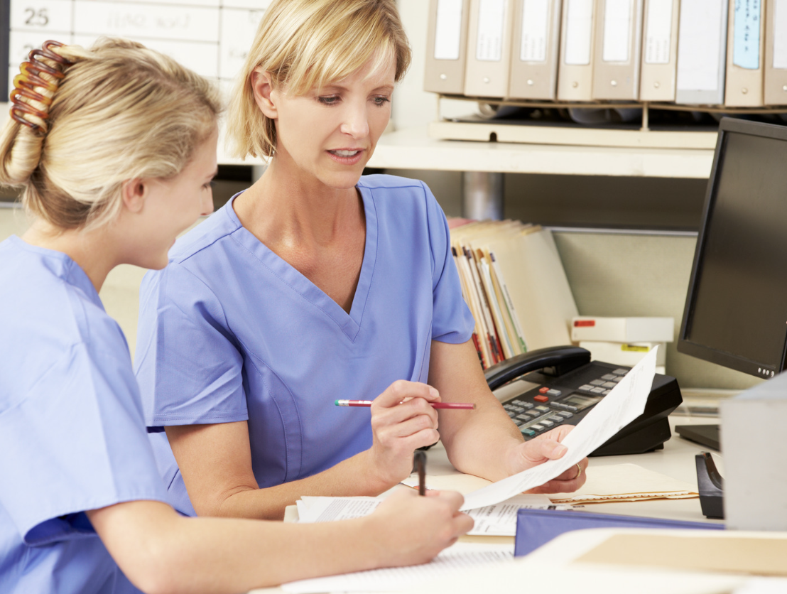 2 nurses working on paperwork in doctor office. best playing travel nurse jobs.